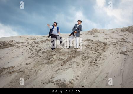 I talebani stanno pianificando attacchi terroristici con armi. Soldato maschio arabo in un headdress fatto del keffiyeh nazionale con le armi nelle sue mani. Foto Stock