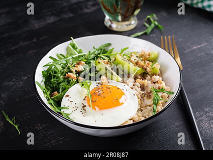 Porridge di farina d'avena con uova arrosto, kiwi, rucola e semi di lino. Colazione sana per abbassare il colesterolo. Foto Stock