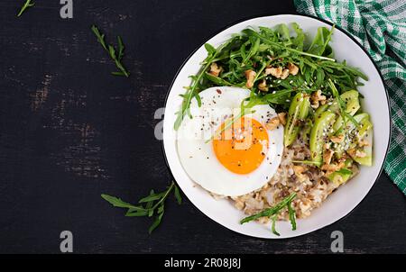 Porridge di farina d'avena con uova arrosto, kiwi, rucola e semi di lino. Colazione sana per abbassare il colesterolo. Vista dall'alto, disposizione piatta Foto Stock