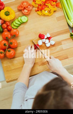 La donna per affettare le verdure sul bordo di taglio Foto Stock