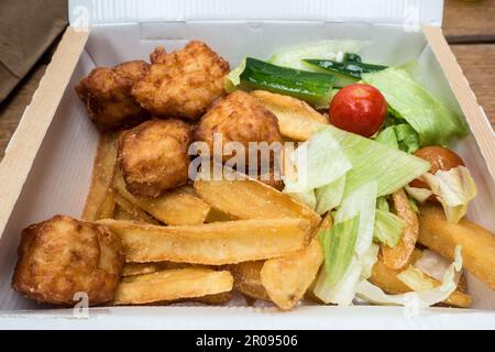 Pepite di pollo e patatine con insalata in una scatola decomponibile Foto Stock