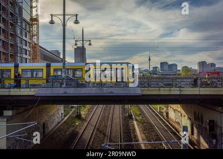 Un tram giallo che passa sopra Warschauer Brücke, (ponte Warschauer) a Warschauer Strasse, Friedrichshain, Berlino, Germania Foto Stock