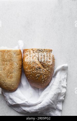 Pagnotta di pane artigianale con semi di sesamo tagliati a metà, vista dall'alto del pane rivestito di sesamo, pane sandwich tagliato a metà Foto Stock