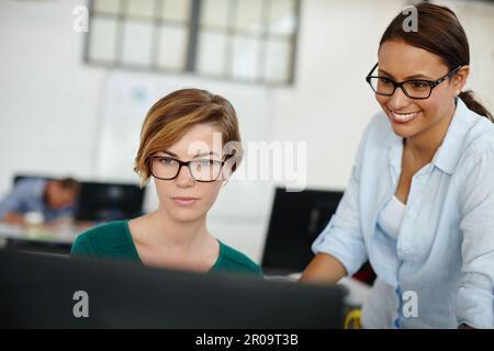 Ottenere il contributo di un collega su un progetto. due designer femminili che lavorano insieme al computer. Foto Stock