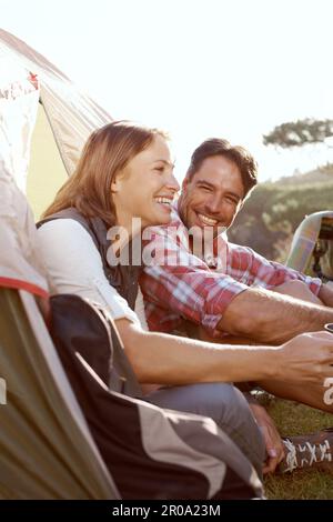 Innamorati l'uno dell'altro e della natura. Una giovane coppia seduta accanto alla tenda durante un viaggio in campeggio. Foto Stock