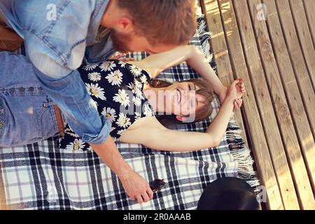Non possono ottenere abbastanza l'uno dell'altro. una giovane coppia affettuosa sdraiata su una coperta all'aperto. Foto Stock