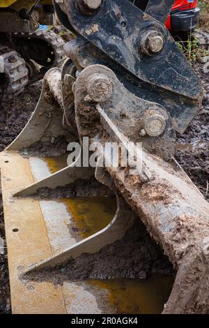 Una grande scavatrice, con una pala attaccata al suo pesante-macchinario, è parcheggiata in un cantiere di impianto pronto per l'uso. Foto Stock