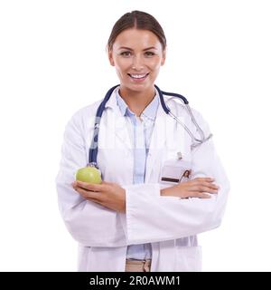 Prevenire è meglio che curare. Ritratto di un bel giovane medico in piedi con le braccia piegate e tenendo una mela su uno sfondo bianco. Foto Stock
