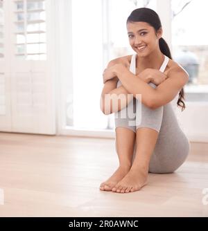 Sentirsi in forma e felice. Ritratto di una bella giovane donna seduta sul pavimento a casa. Foto Stock