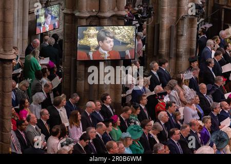 Gli ospiti e i membri della congregazione osservano i rituali di incoronazione sugli schermi all'interno dell'Abbazia di Westminster del Re Carlo III e della Regina Consorte. Foto Stock