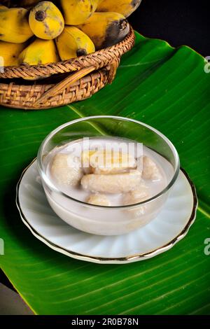 Banana in latte di cocco. Tradizionali dessert thailandesi in una ciotola su una foglia di banana con banana. Foto Stock