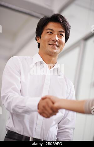 Fare un affare. un bell'uomo d'affari asiatico che scuote le mani con un'altra persona. Foto Stock