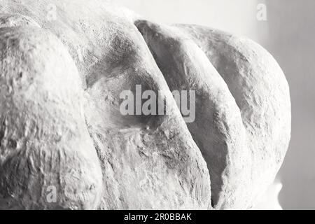 Un frammento di gesso della scultura della testa umana su sfondo grigio. Primo piano con ritaglio frontale con spazio di copia. Foto Stock