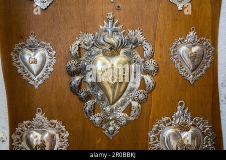 Ex voto offerto in devozione per le grazie ricevute dalla Santissima Trinità di Vallepietra. Fotografie e cuori in argento. Vallepietra, Lazio Foto Stock