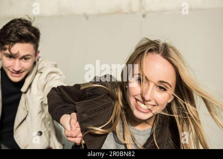 Ragazza adolescente che tira il suo ragazzo con la mano, Monaco, Baviera, Germania Foto Stock