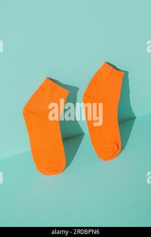 Calzini arancioni nuovi su sfondo verde menta. Foto Stock