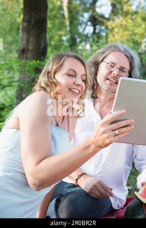 Coppia al pic-nic utilizzando tablet, mangiare anguria tra la natura, Baviera, Germania Foto Stock