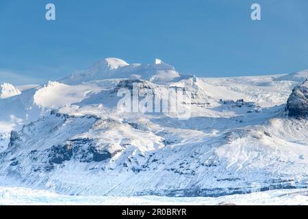 Vista ravvicinata della cima innevata di Hvannadalshnukur nel Parco Nazionale di Vatnajökull, vicino a Svinafell, Islanda, contro un cielo blu chiaro Foto Stock