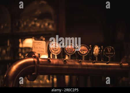 Un primo piano di birreria retrò si pompa in un pub scarsamente illuminato con uno sfondo sfocato Foto Stock