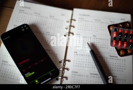 Libro di note mensile del pianificatore con penna della medicina e un telefono mobile con la notifica su esso Foto Stock
