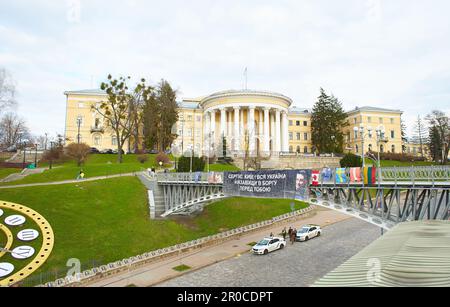 Kyiv, Ucraina - 03.27.2023: Ponte con poster e Galleria dei ritratti per la memoria di Eroi del Cielo cento, memoriali, orologio, Palazzo della cultura a Maidan Foto Stock