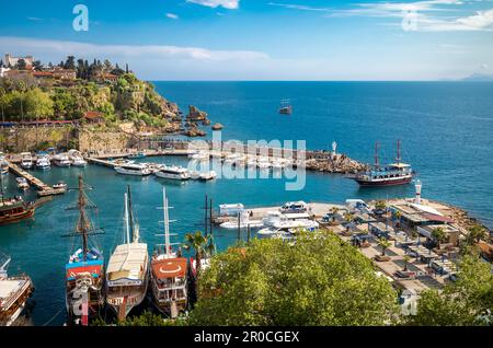 Una barca turistica naviga con grazia attraverso l'ingresso dell'antico porto di Kaleici, l'affascinante città vecchia di Antalya, in Turchia, in una giornata di sole. Il Foto Stock