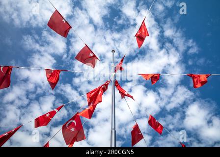 Una splendida esposizione di bandiere turche puntate su un palo in Antalya, Turchia (Turkiye) crea una scena vibrante e dinamica contro il cielo blu su un sole Foto Stock