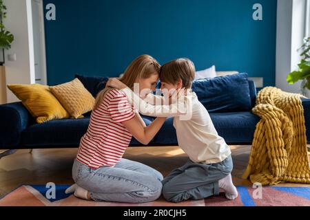 Affettuoso empathic che cura la mamma ed il figlio teen abbracciano insieme siedono sul pavimento nel soggiorno a casa. Foto Stock