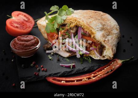 Deliziosa pita farcita con carne tenera, verdure fresche e spezie aromatiche Foto Stock