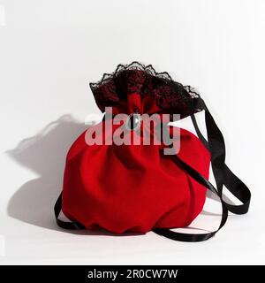 Una borsa rossa vivace con un lussuoso rivestimento in pizzo nero isolato su uno sfondo bianco Foto Stock