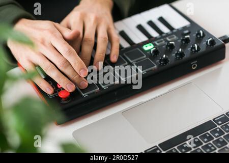 Vista dall'alto del produttore o dell'arrangiatore di musica utilizzando un computer portatile e una tastiera midi e altre apparecchiature audio per creare musica in casa. Beat making e. Foto Stock