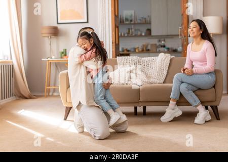 Daddy coreano gioioso abbracciando la figlia piccola a casa, celebrando la riunione Foto Stock