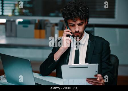 Uomo d'affari che effettua la chiamata telefonica per discutere i dettagli del rapporto con il collega, concetto di scadenza Foto Stock