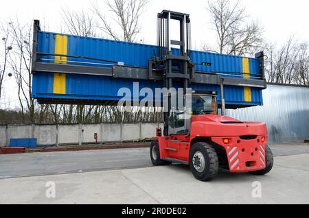 Caricatore a forche elettrico che trasporta container in un deposito di container, impianti della stazione ferroviaria. Kiev, Ucraina. Foto Stock