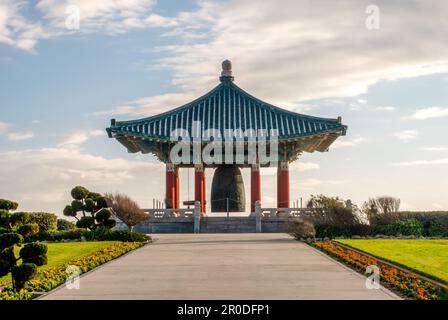 Una campana d'amicizia coreana disegnata in modo ornato in un lussureggiante parco verde Foto Stock