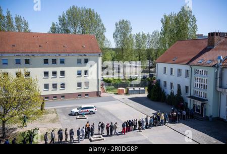 08 maggio 2023, Brandeburgo, Eisenhüttenstadt: I migranti si trovano in fila presso la struttura di accoglienza iniziale del Brandeburgo (EAE) a Eisenhüttenstadt. Il gruppo parlamentare CDU/CSU e il ministro dell'interno del Brandeburgo hanno visitato una prima struttura di accoglienza (EAE). Foto: Hannes P Albert/dpa Foto Stock