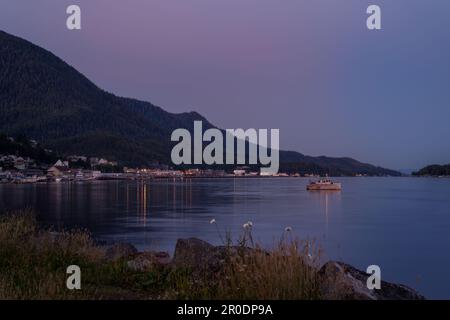 Una scena idilliaca al crepuscolo con diverse barche ormeggiate in primo piano e maestose montagne sullo sfondo Foto Stock