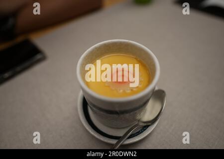 Una tazza di ceramica bianca riempita con un delizioso Chawanmushi, un tradizionale piatto giapponese alla crema di uova al vapore Foto Stock