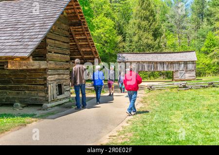 Cades Cove, Tennessee, Stati Uniti – 24 aprile 2023: Immagine orizzontale dei visitatori che esaminano fienili dietro la Becky Cable House a Cades Cove. Foto Stock