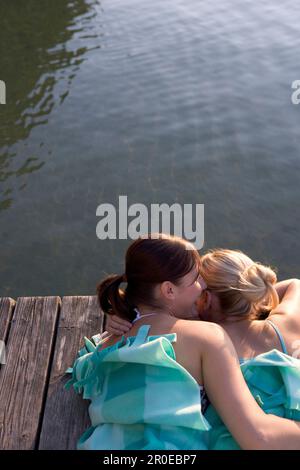 Due giovani donne sdraiate sul lungomare in coperta, Monaco, Baviera Foto Stock