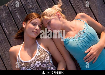 Due giovani donne sdraiate sul lungomare, Monaco, Baviera Foto Stock