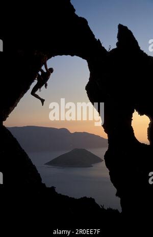 Maschio free climber scalando roccia faccia, Kalymnos, Dodecanese, Grecia Foto Stock