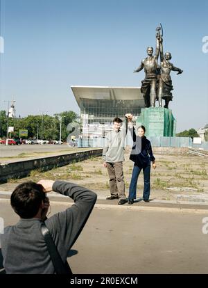 Turisti che scattano foto di fronte al monumento Worker e Kolkhoz Woman, ricostruito Padiglione Russo da Expo 67 in background, All-Russian Exhibition CEN Foto Stock