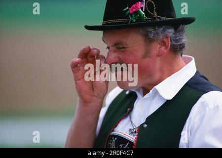 Uomo in abiti tradizionali che prende il tabacco da fiuto, Lago di Chiemsee, alta Baviera, Germania Foto Stock