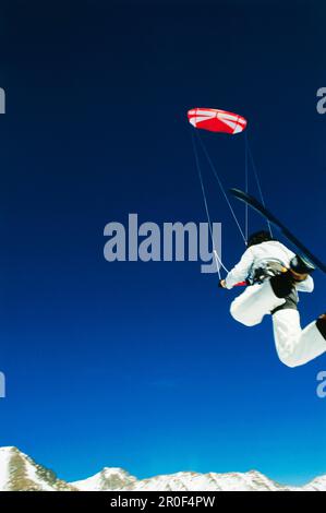 Uomo kiteboarding in neve, Jump, Lermoos, Lechtaler Alpen, Tirolo, Austria Foto Stock