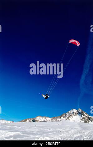 Uomo kiteboarding in neve, Jump, Lermoos, Lechtaler Alpen, Tirolo, Austria Foto Stock