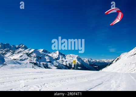 Uomo kiteboarding nella neve, Lermoos, Lechtaler Alpen, Tirolo, Austria Foto Stock