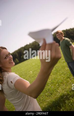 Giovane donna che lancia aeroplano di carta sul prato Foto Stock