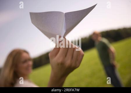 Giovane donna che lancia aeroplano di carta sul prato Foto Stock