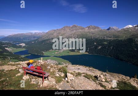 Escursionista riposante su una panchina rossa con vista sui laghi Engadin, St. Moritz e Bernina, alta Engadina, Grigioni, Svizzera Foto Stock